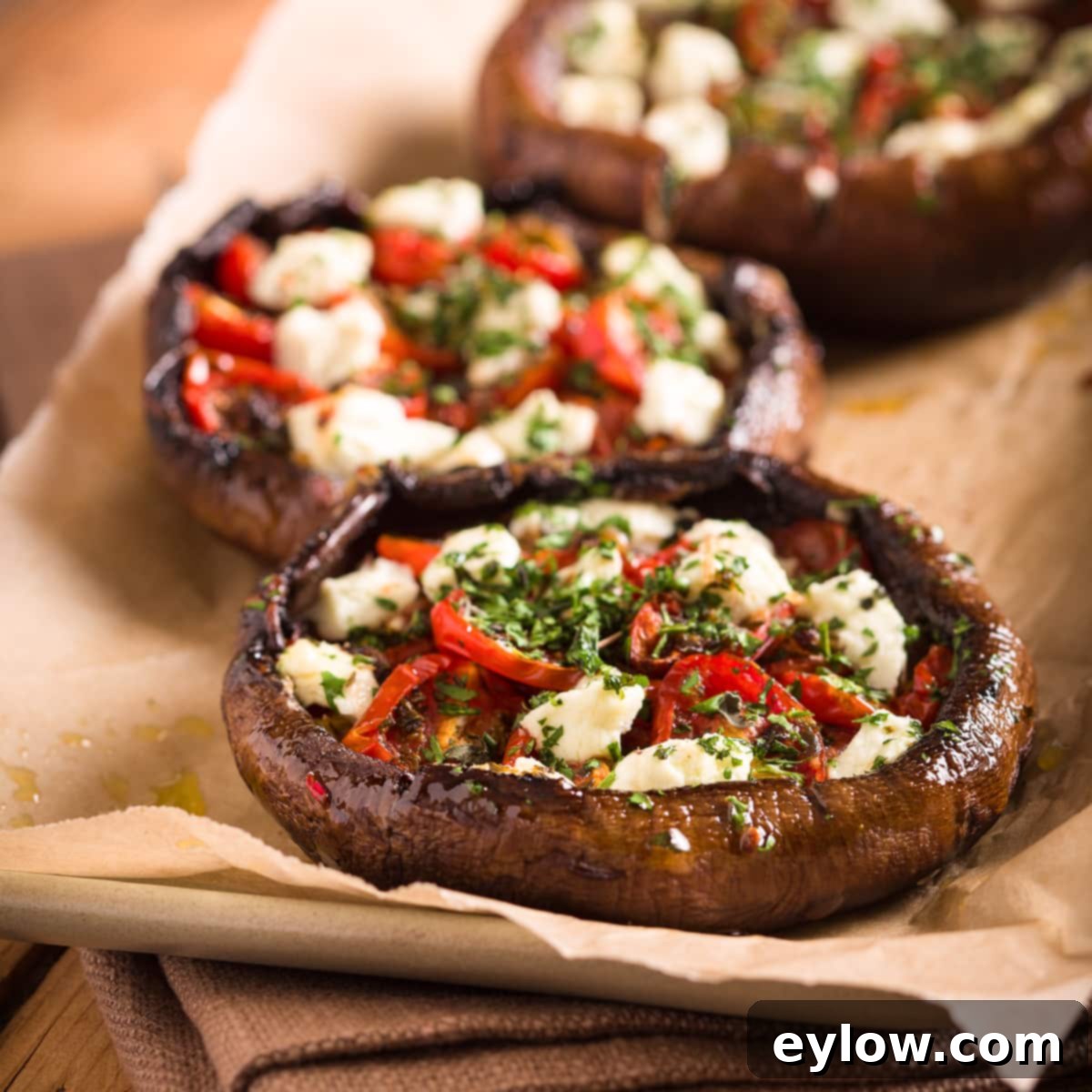 Stuffed mushrooms close up filled with roasted tomatoes, goat cheese, and green herbs, showcasing the vibrant and delicious filling.