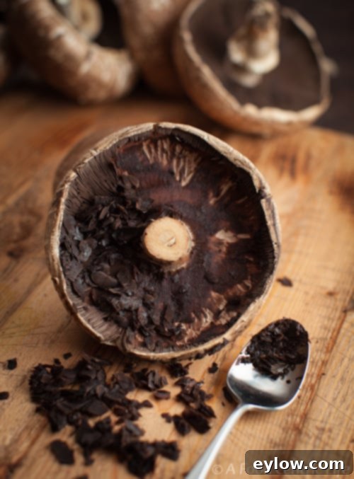 Cleaning the mushroom caps of gills using a spoon to create a clean cavity for filling.