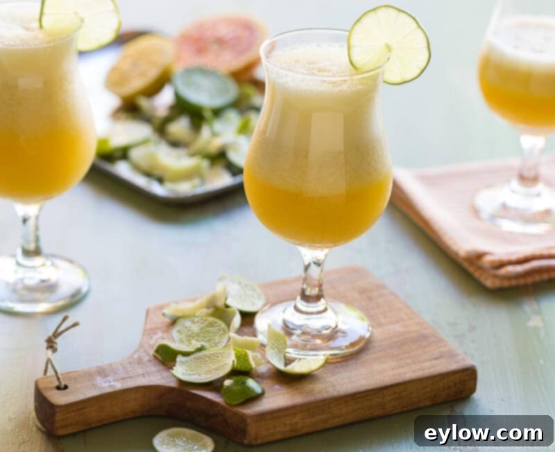 Vibrant mango mocktail margarita in a stemmed glass, garnished with a fresh lime wedge. A truly refreshing non-alcoholic drink.