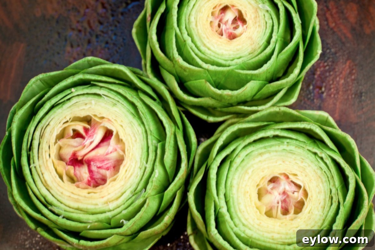 Bright green raw artichokes with trimmed tops and stems, ready for steaming.