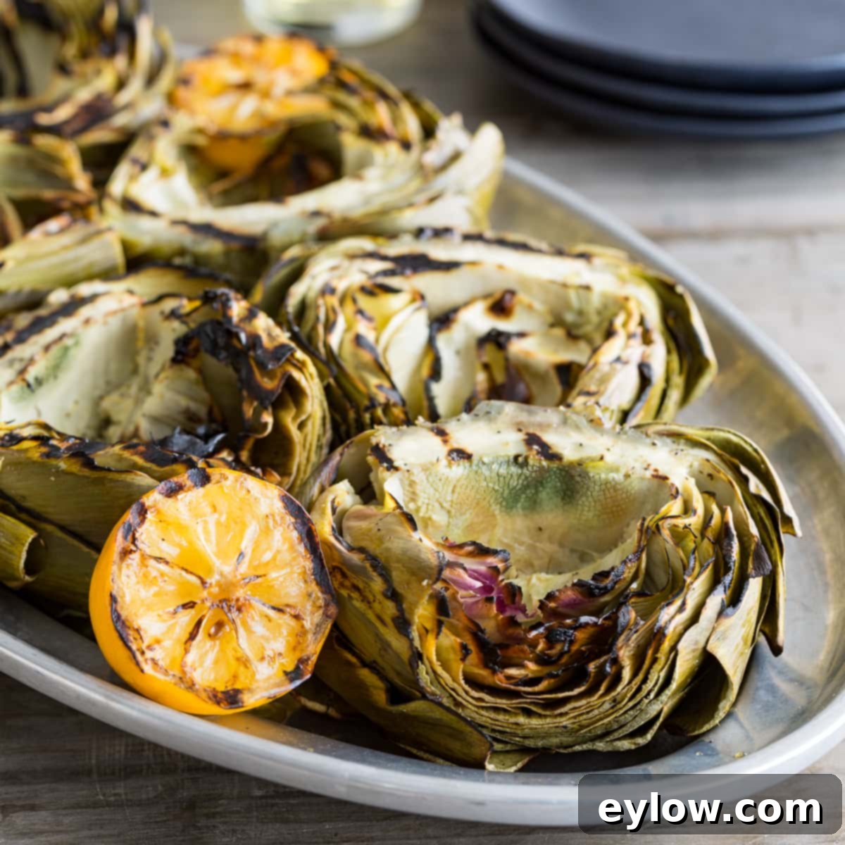 Grilled artichoke halves beautifully charred and served with grilled lemon wedges.