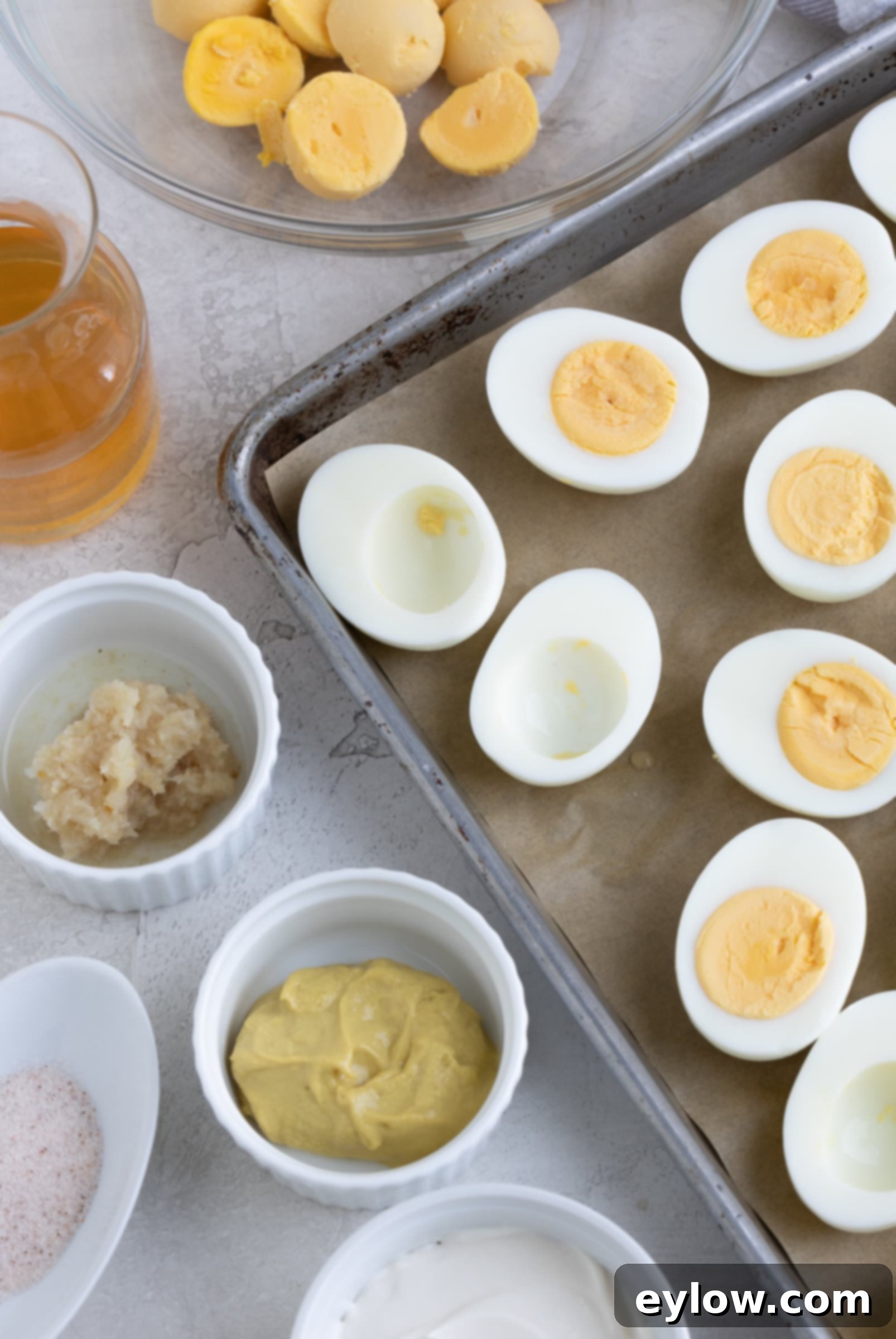 The Ultimate Deviled Eggs 5 A baking sheet with hard boiled egg halves for making deviled eggs, with yolks, vinegar, mustard.