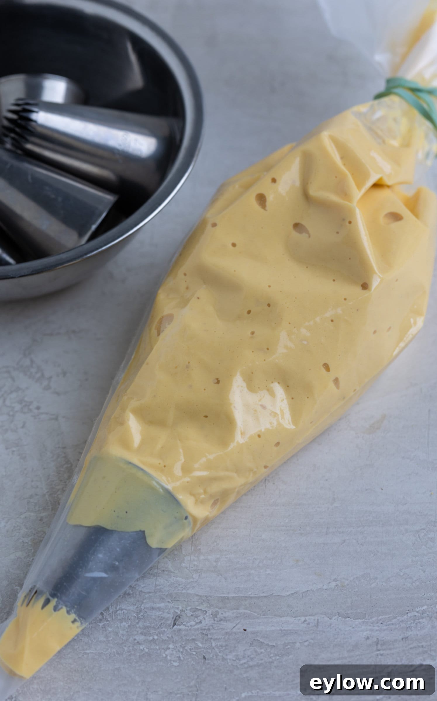 The Ultimate Deviled Eggs 7 Deviled egg filling in a clear piping bag with a star tip for piping.