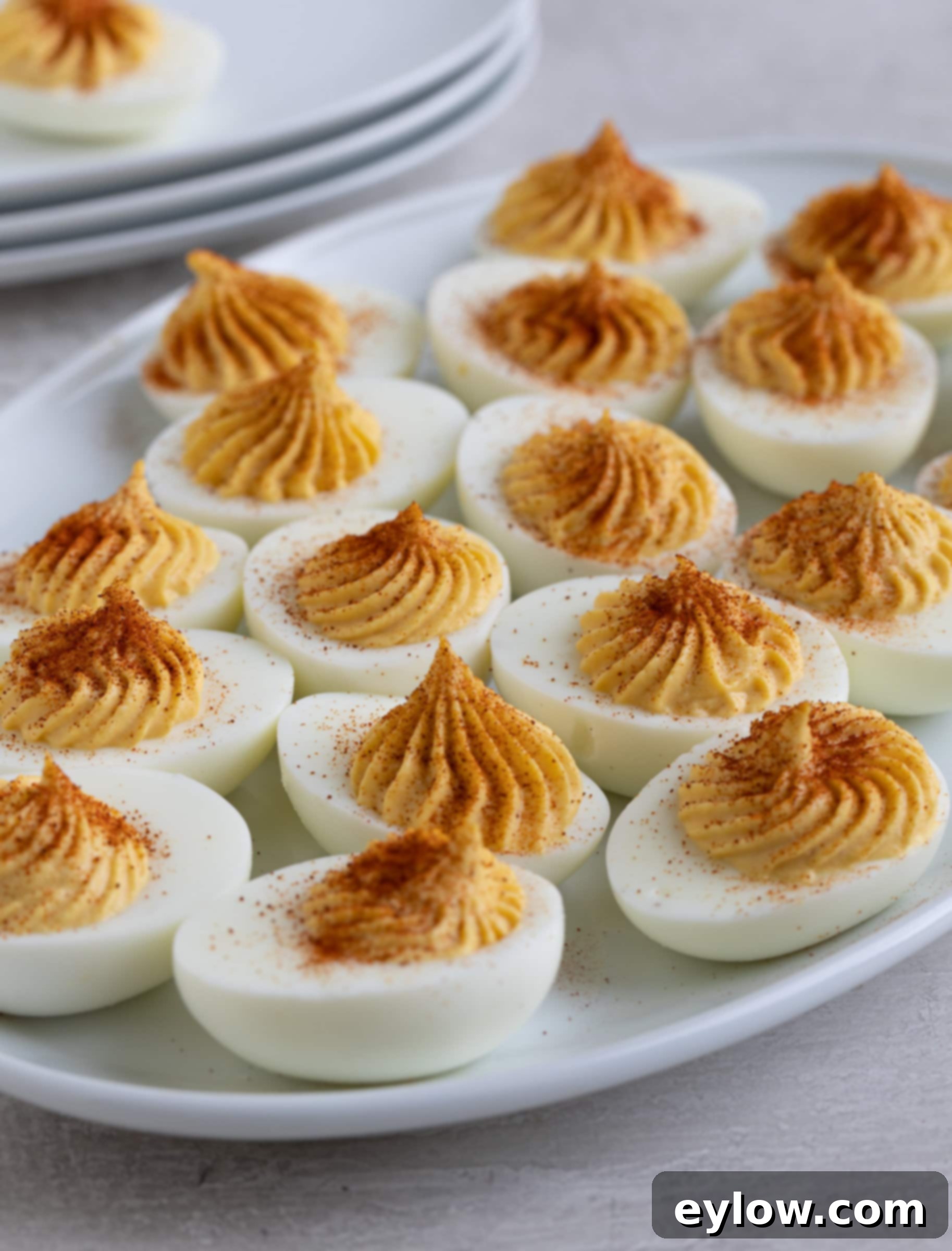 The Ultimate Deviled Eggs 9 A platter of finished deviled eggs topped with red paprika as garnish.