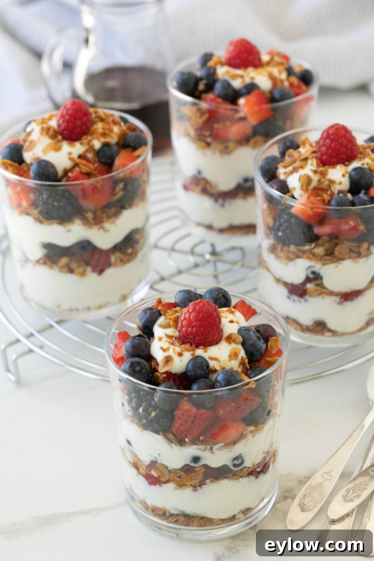 Colorful Greek yogurt parfaits in glasses with layers of granola, yogurt, and berries.
