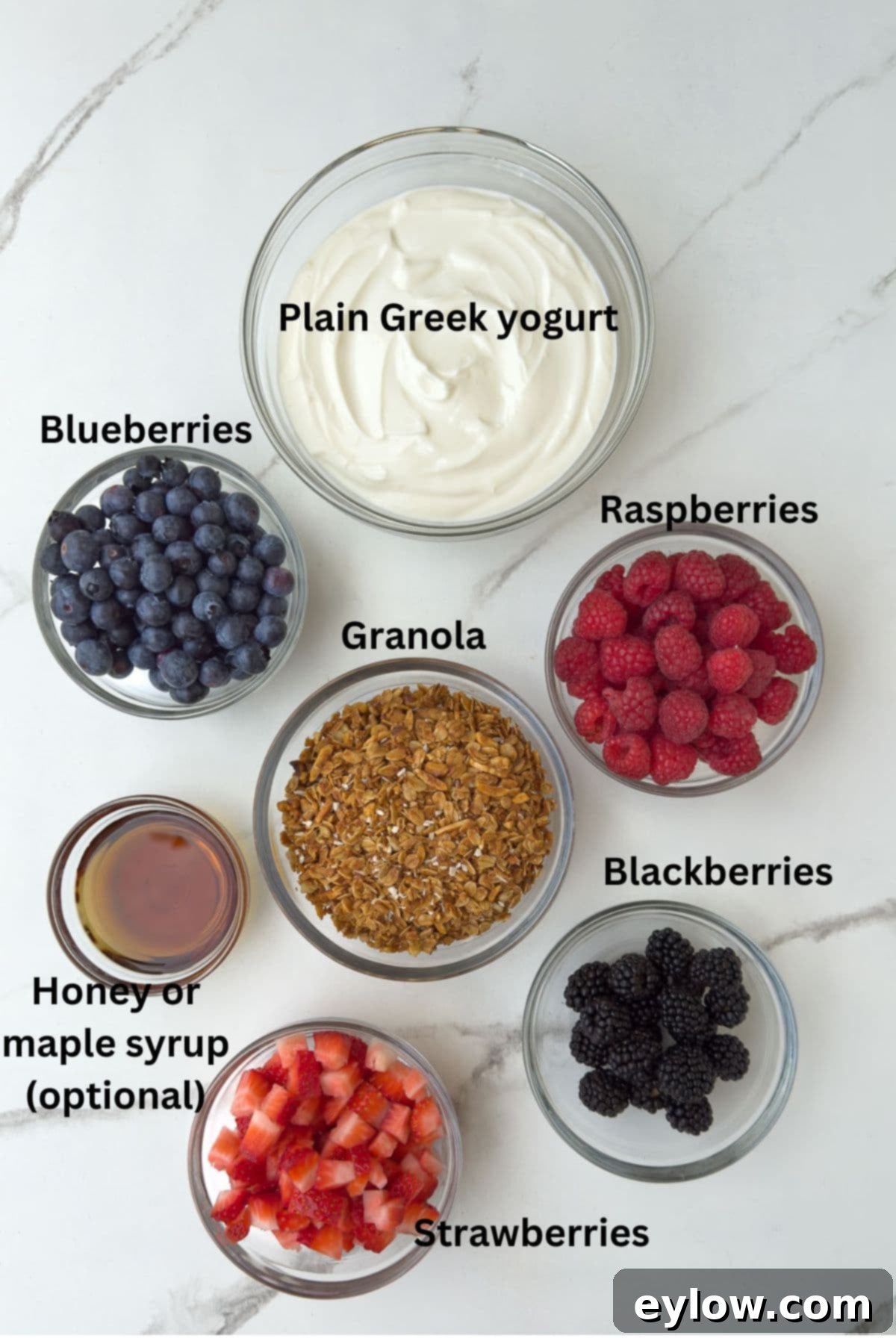 Ingredients for yogurt parfaits in glass bowls on the counter.