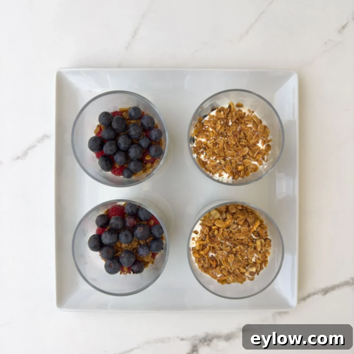 The next layer of ingredients in a yogurt parfait, berries and granola with yogurt.