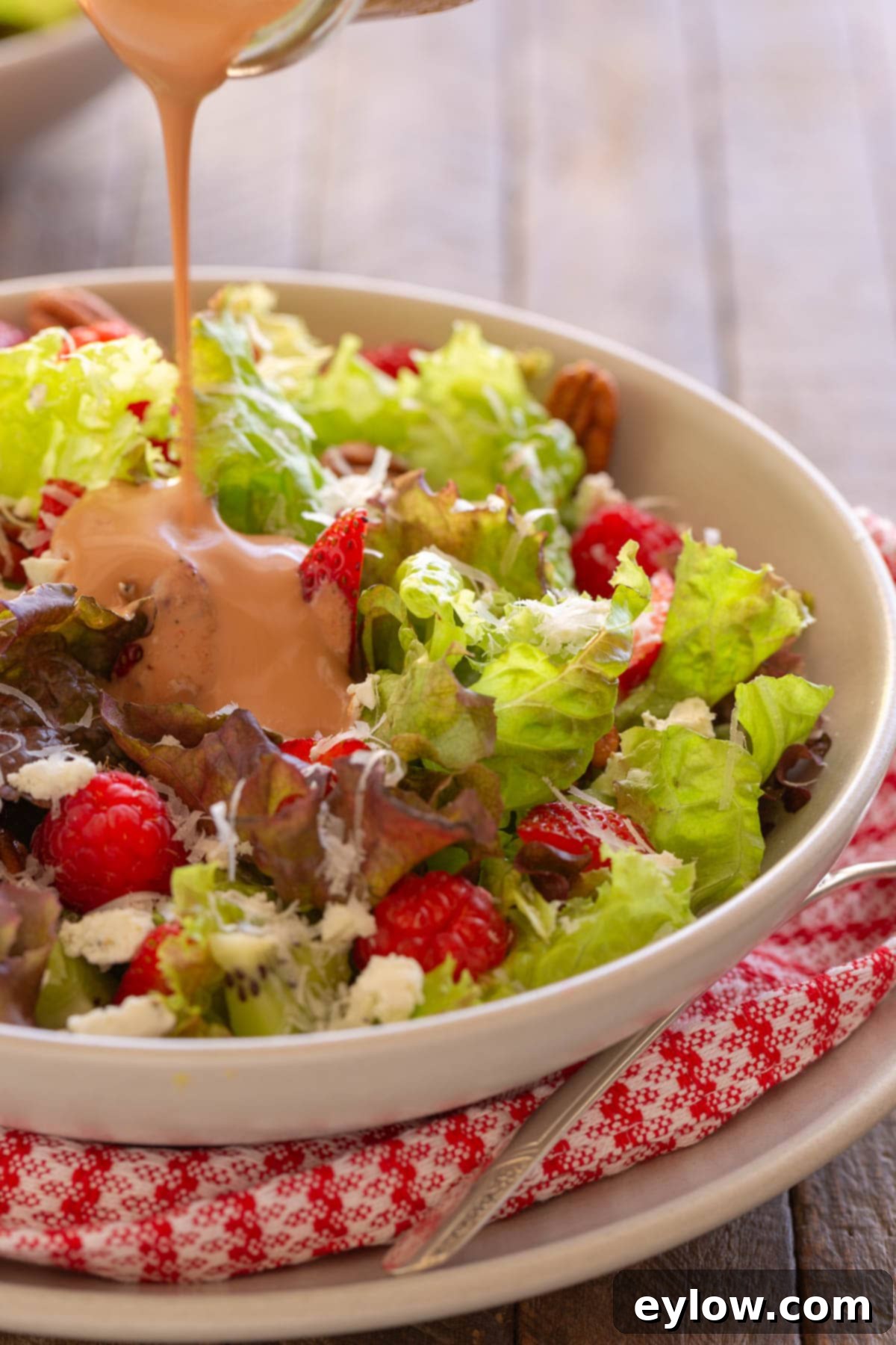 Strawberry goat cheese salad with strawberry vinaigrette pouring over the top.