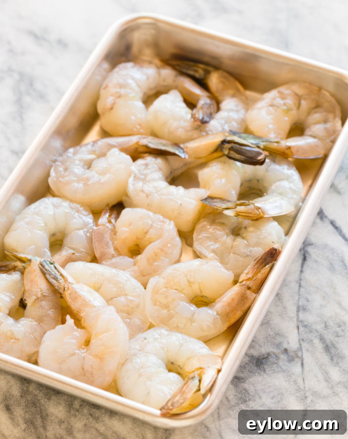 Effortless Coconut Shrimp Curry 3 Raw shrimp peeled and cleaned, arranged neatly on a rimmed baking sheet.