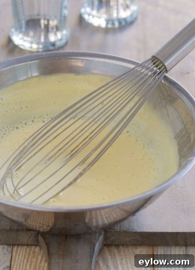 A bowl of fluffy sabayon sauce with a whisk in process.