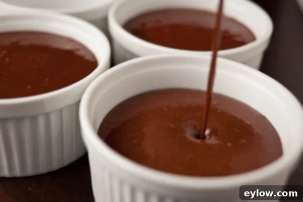 Bittersweet chocolate pudding pouring into ramekins.
