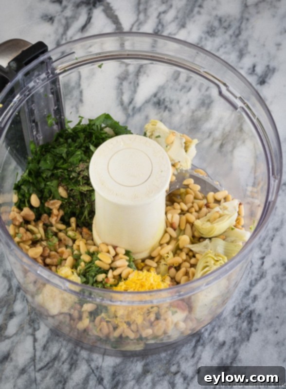 All the ingredients for the hot artichoke dip prepped and placed in a food processor bowl, ready for blending.