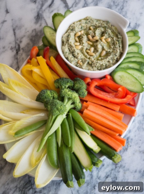 A vibrant crudité platter featuring fresh vegetables and a bowl of hot artichoke dip, ready for entertaining.