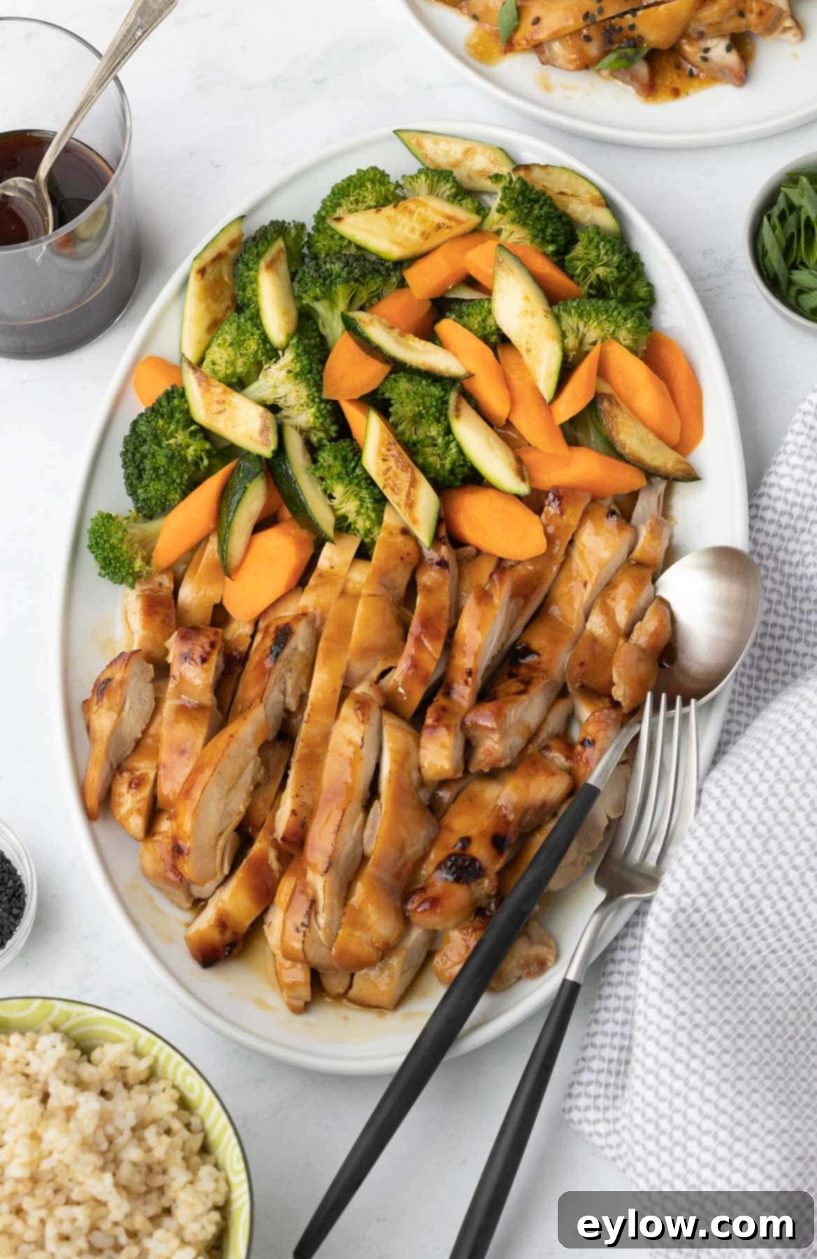 A platter of sliced teriyaki chicken thighs with vegetables. 
