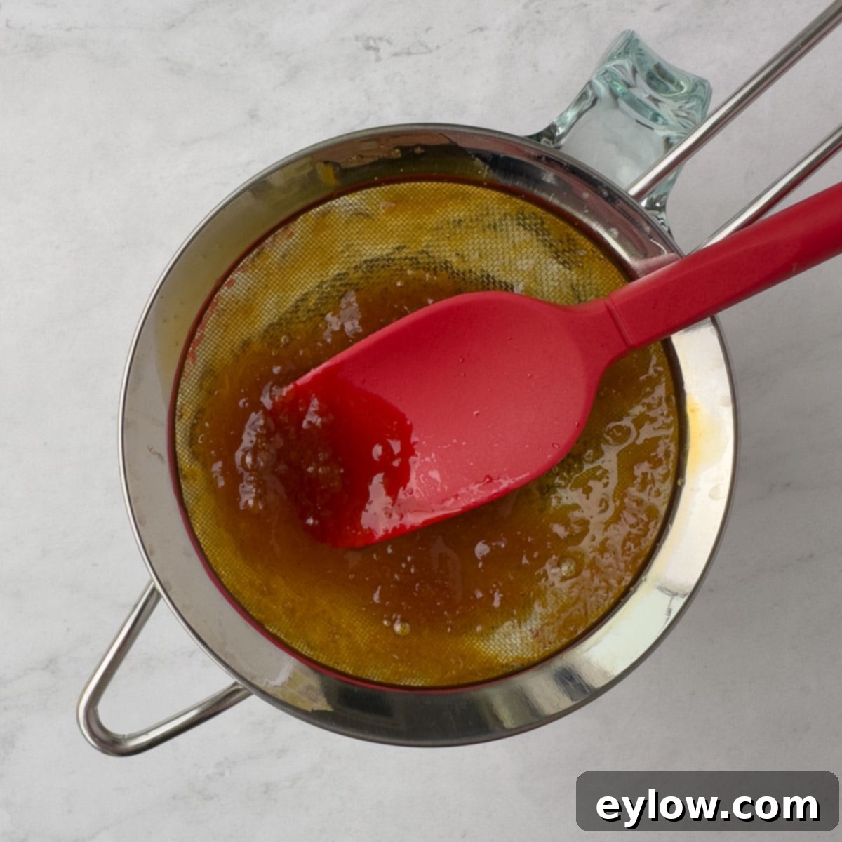 Straining the sauce into a glass measuring cup for a smooth sauce.