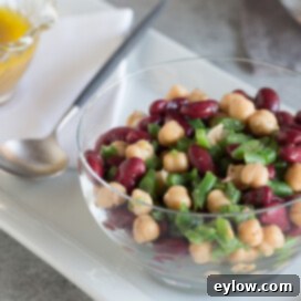 Effortless Zesty Three Bean Salad 13 Colorful 3-bean salad in a glass bowl with a serving spoon.