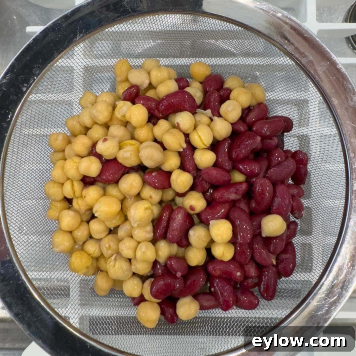 Effortless Zesty Three Bean Salad 8 Gold and red beans in a stainless steel sieve draining in the sink.