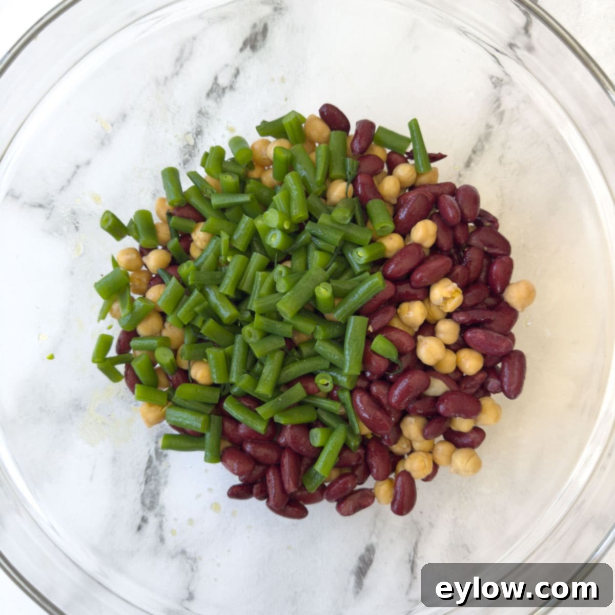 Effortless Zesty Three Bean Salad 9 Kidney beans, green beans, and chickpeas mixed in a glass bow.
