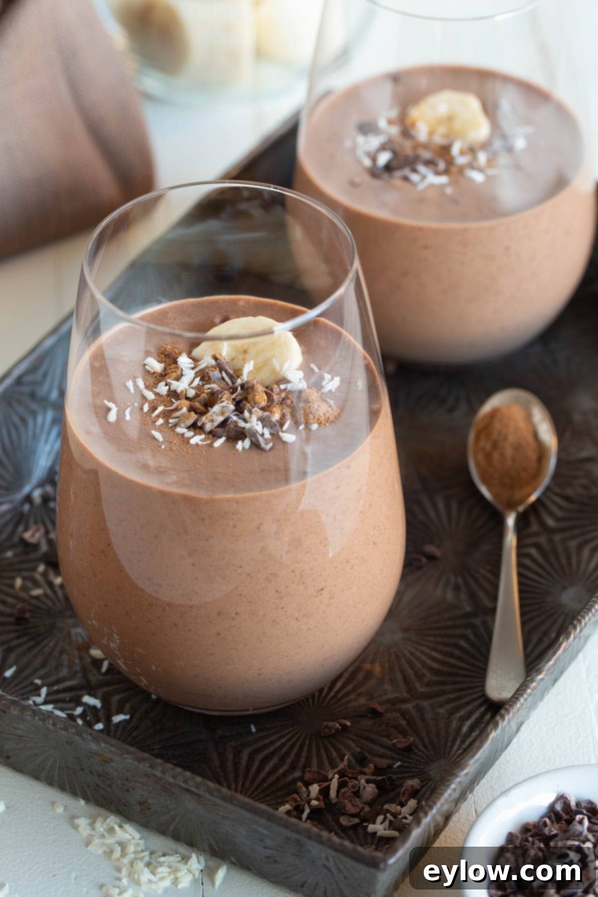 Velvet Chocolate Banana Dream 2 Creamy chocolate smoothies in glasses topped with banana slices and cacao nibs, ready to be enjoyed.