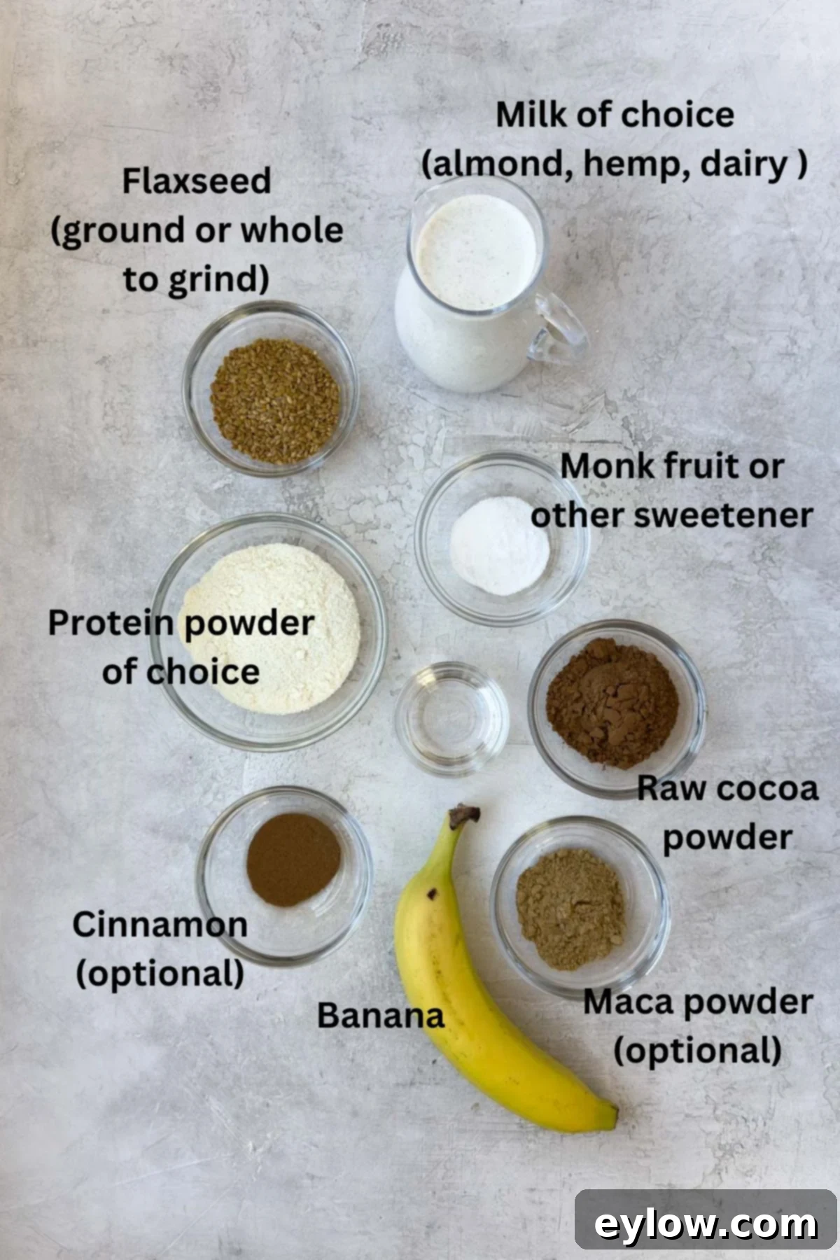 Velvet Chocolate Banana Dream 3 Various ingredients for a chocolate smoothie laid out on a gray counter, including bananas, cacao powder, and milk.