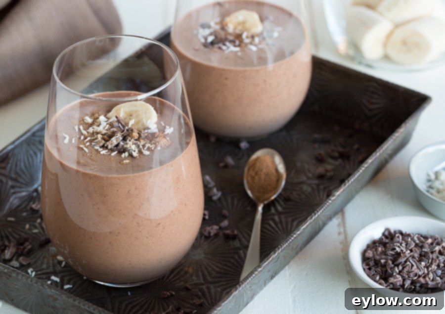 Velvet Chocolate Banana Dream 6 Two glasses of creamy chocolate smoothies topped with cacao nibs, ready to be served.