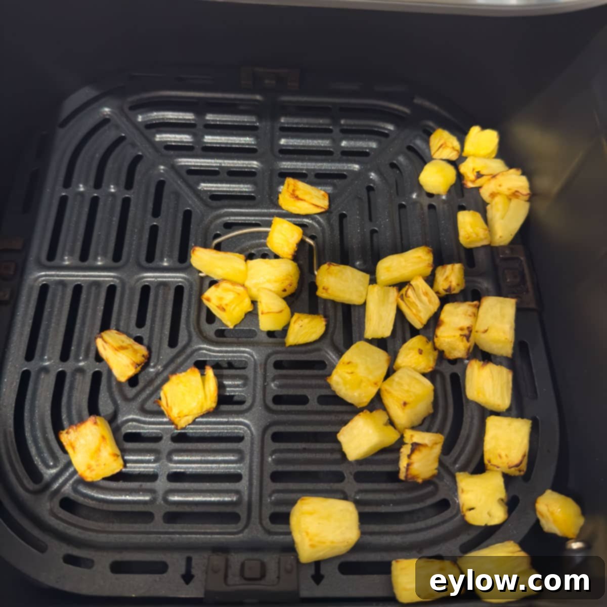 Hawaiian Goat Cheese Salad 5 Golden yellow pineapple chunks in an air fryer basket with beautifully browned, caramelized edges, showing how cooking enhances their sweetness and texture.