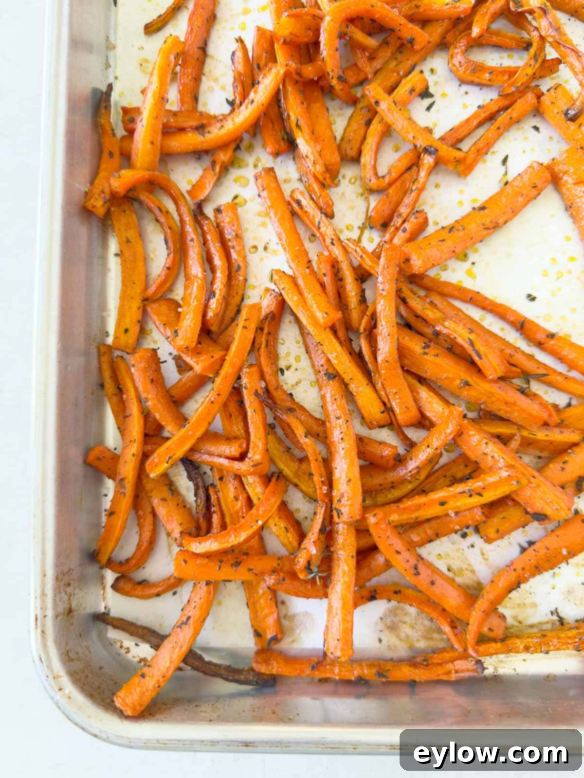 Maple roasted carrots on a baking tray, glistening and ready to serve, garnished with fresh thyme.