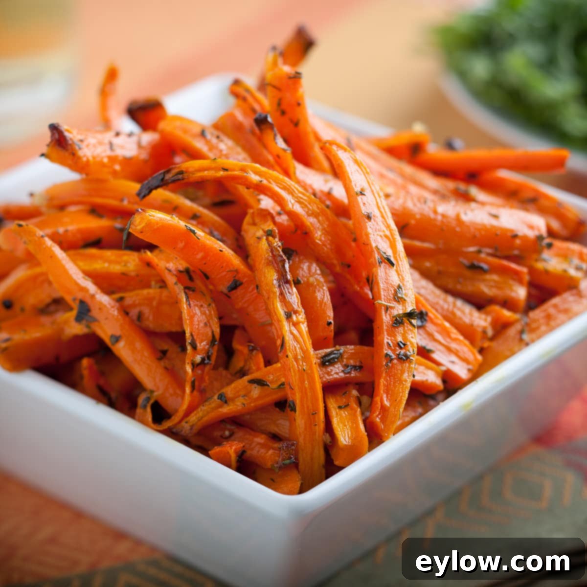 Close up of perfectly roasted carrots with fresh thyme sprigs and glistening maple glaze.