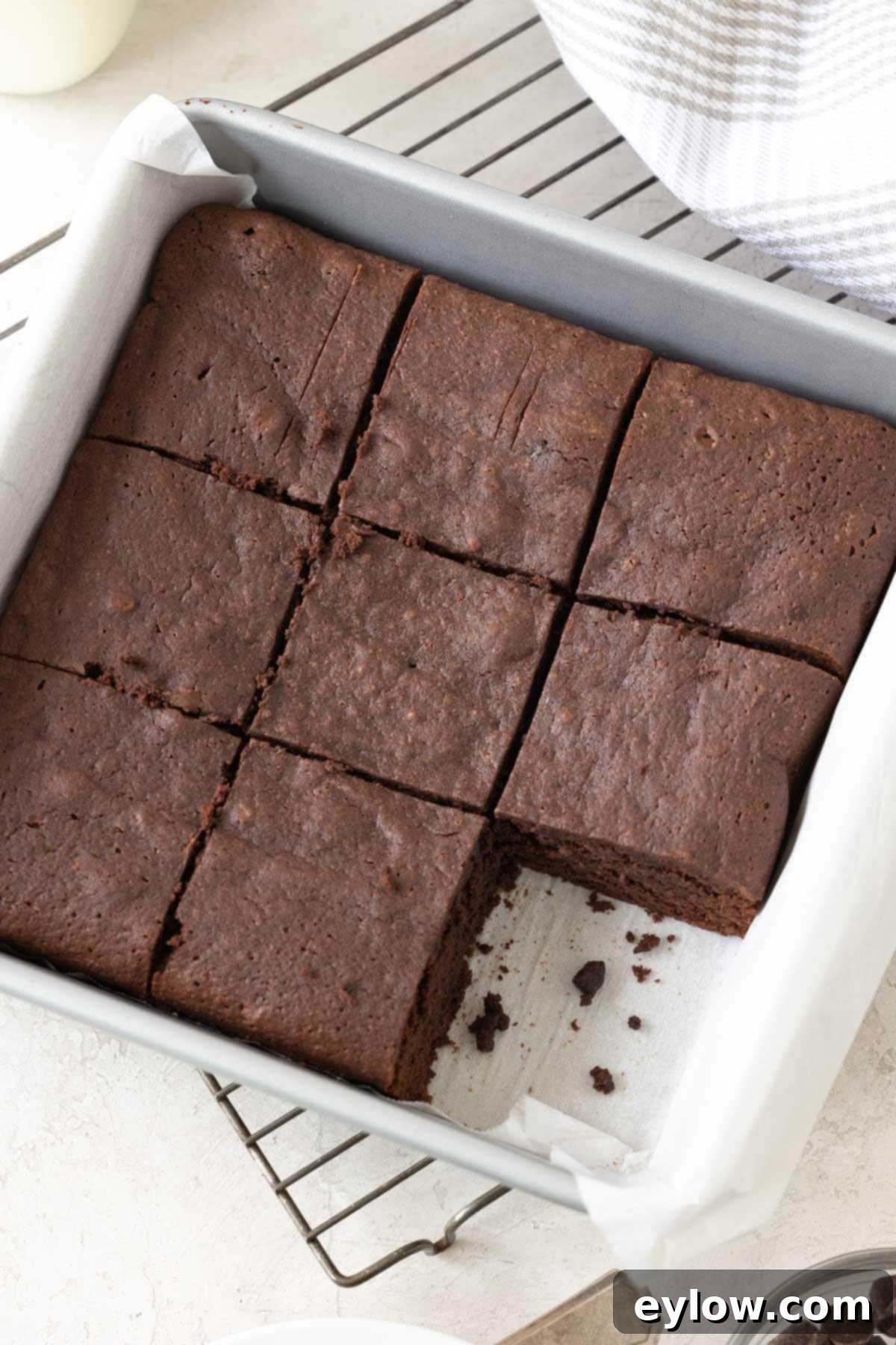 Decadent Fudgy Gluten-Free Chocolate Brownies 2 Sliced dark chocolate brownies in a square silver baking pan with one piece gone, revealing their fudgy interior.