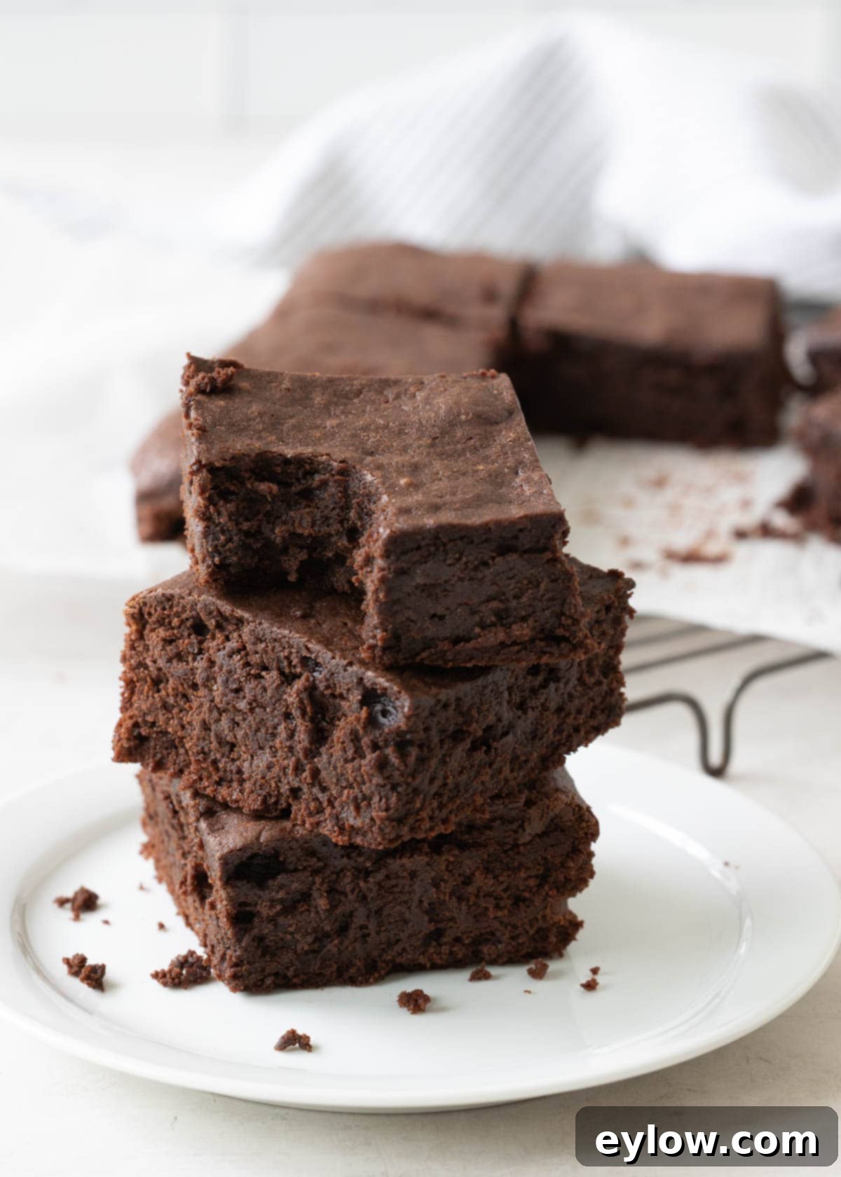 Decadent Fudgy Gluten-Free Chocolate Brownies 11 A stack of three fudgy gluten-free brownies on a small plate, with a bite taken out of the top one.