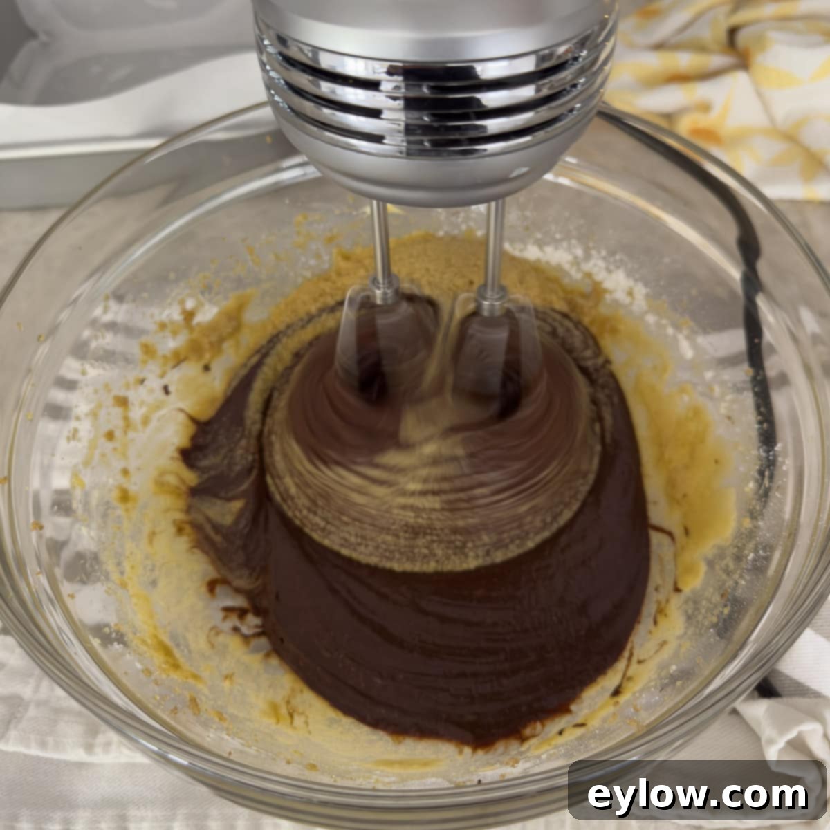 Decadent Fudgy Gluten-Free Chocolate Brownies 7 Mixing chocolate brownie batter with an electric hand mixer in a glass bowl until smooth and well combined.