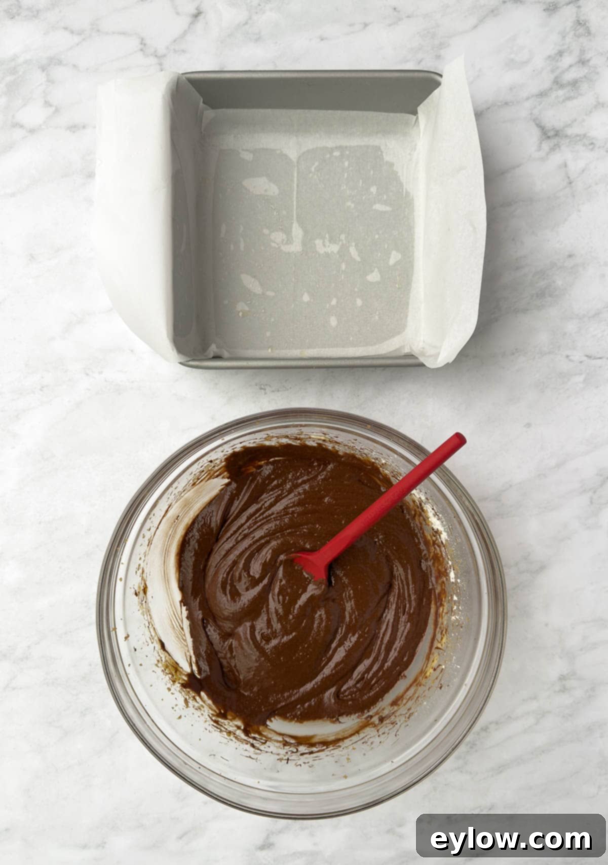 Decadent Fudgy Gluten-Free Chocolate Brownies 8 Thick chocolate brownie batter being scraped into a parchment-lined, light metal square baking pan, ready for the oven.