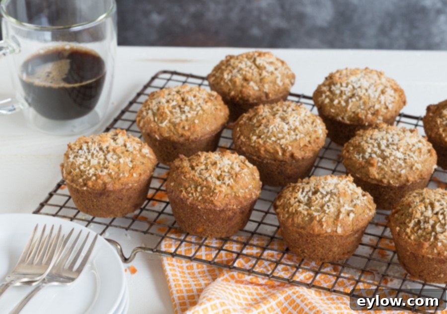 Moist Gluten-Free Dairy-Free Carrot Cake Muffins 5 Warm, freshly baked gluten-free carrot cake muffins cooling on a wire rack, with a cup of coffee in the background.