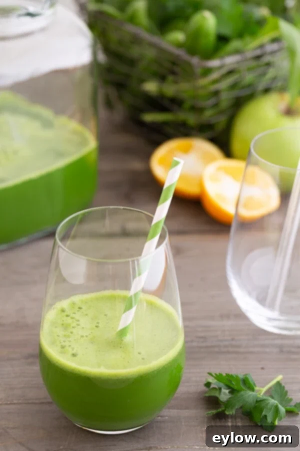 dandy detox green juice in a glass with straw.