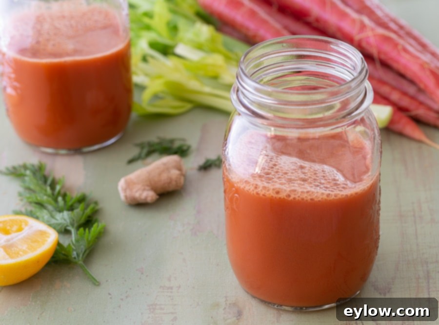 A glass of morning glow carrot celery juice with fresh ingredients in the background