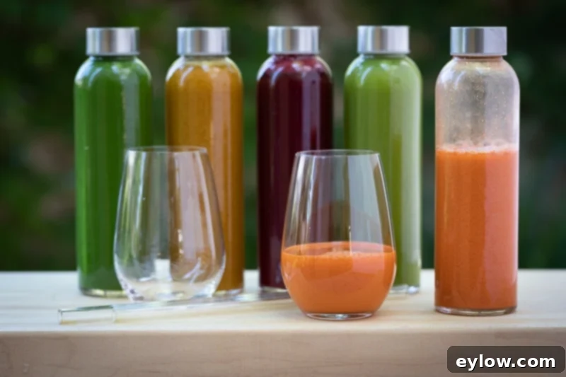 Colorful vegetable juices in glasses and bottles on an outdoor table.