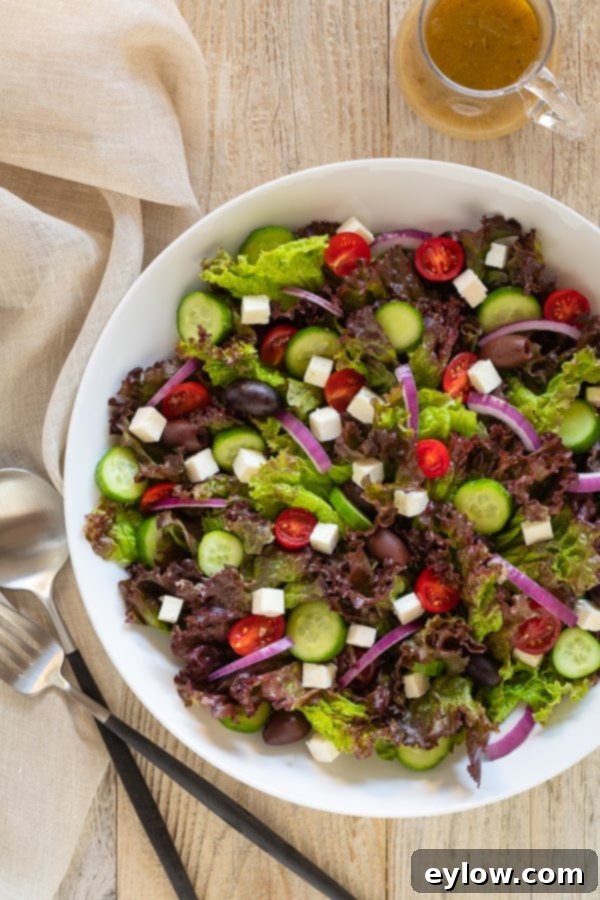 Classic Greek Garden Salad 2 A vibrant leafy green Greek salad in a bowl, showcasing fresh ingredients like lettuce, tomatoes, cucumbers, olives, and feta cheese. Drizzled with a tangy dressing.