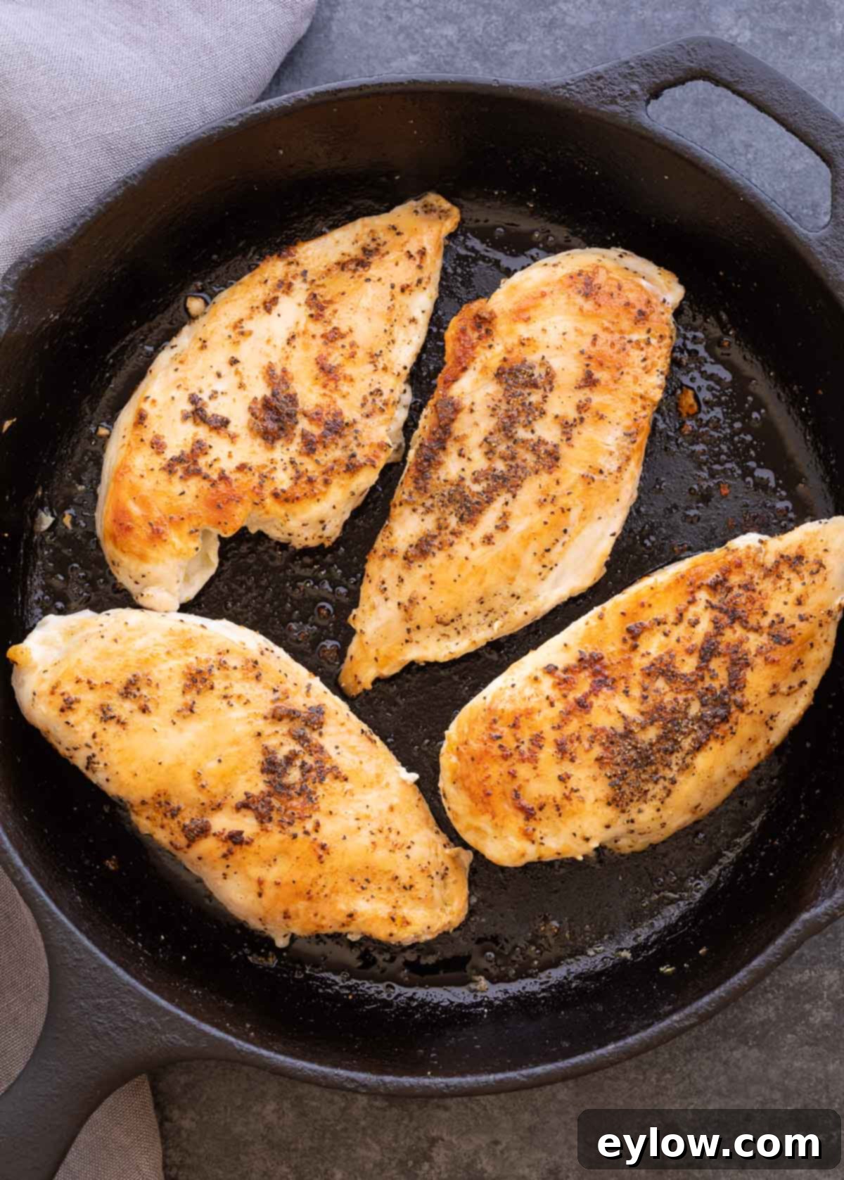 Chicken breasts browning in a cast iron pan before salsa is added.