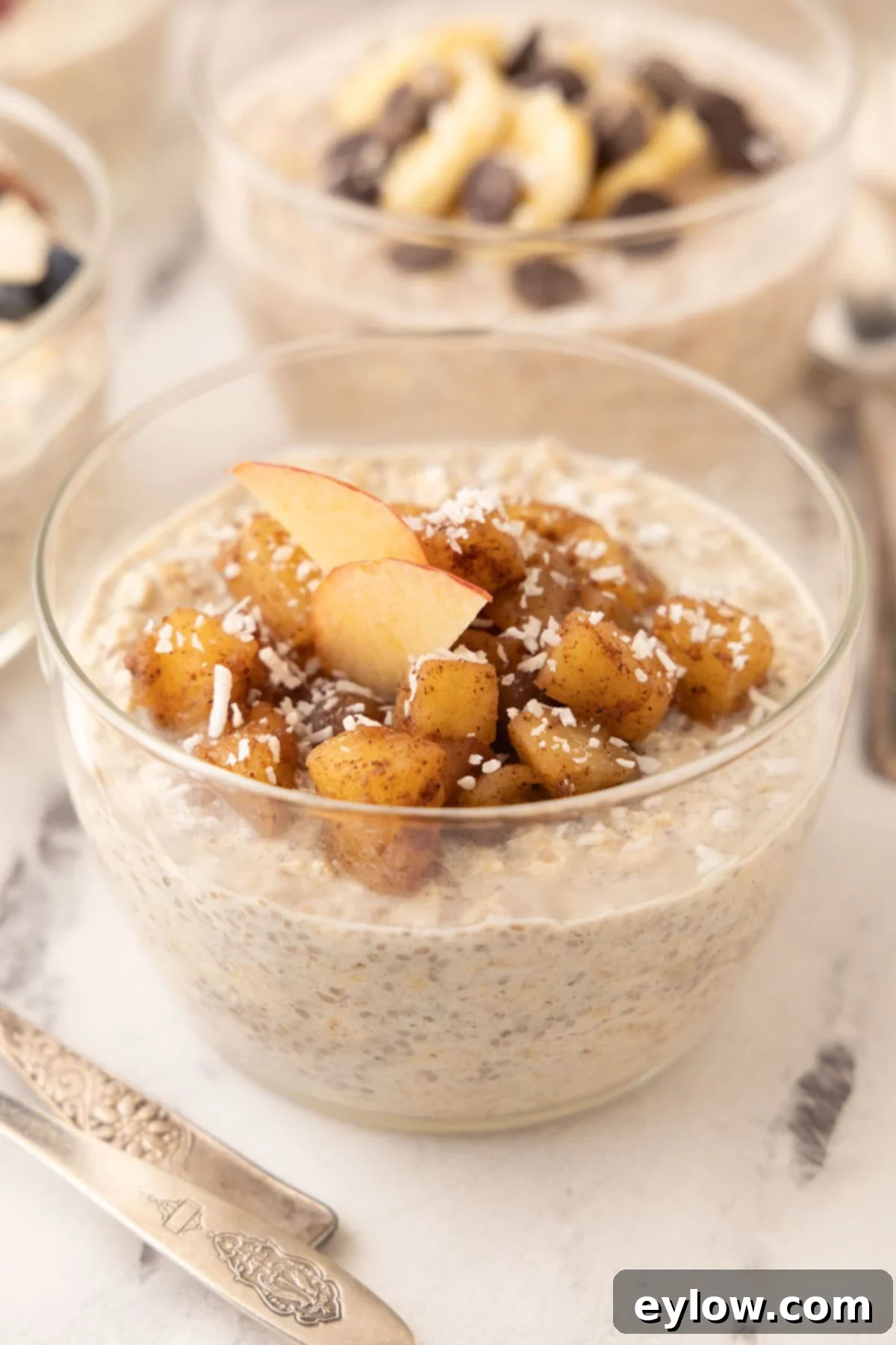 Overnight oats topped with a generous portion of cinnamon apple compote in a clear glass bowl, ready to eat.