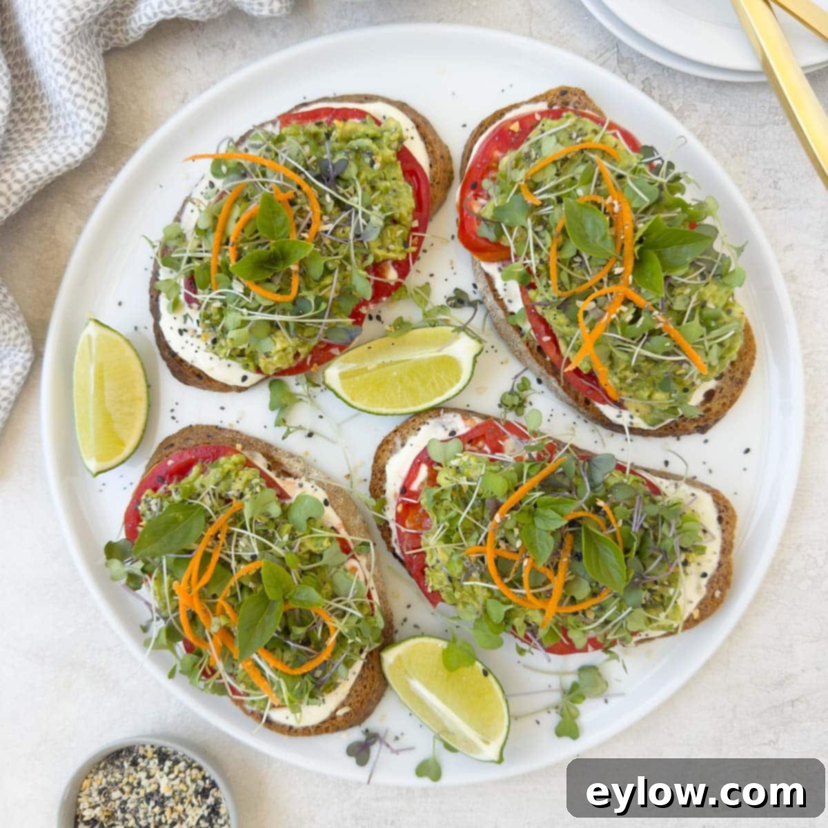 Vibrant Tomato Avocado Toast 8 A close-up of a beautifully assembled avocado tomato toast, garnished with delicate baby greens and fresh basil leaves.