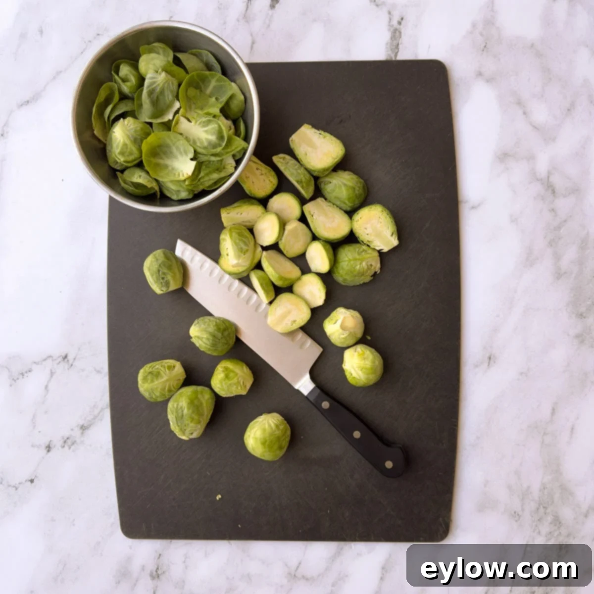 Zesty Lemon and Thyme Brussels Sprouts 3 Prepping Brussels sprouts on a black cutting board with knife, showing halved sprouts.