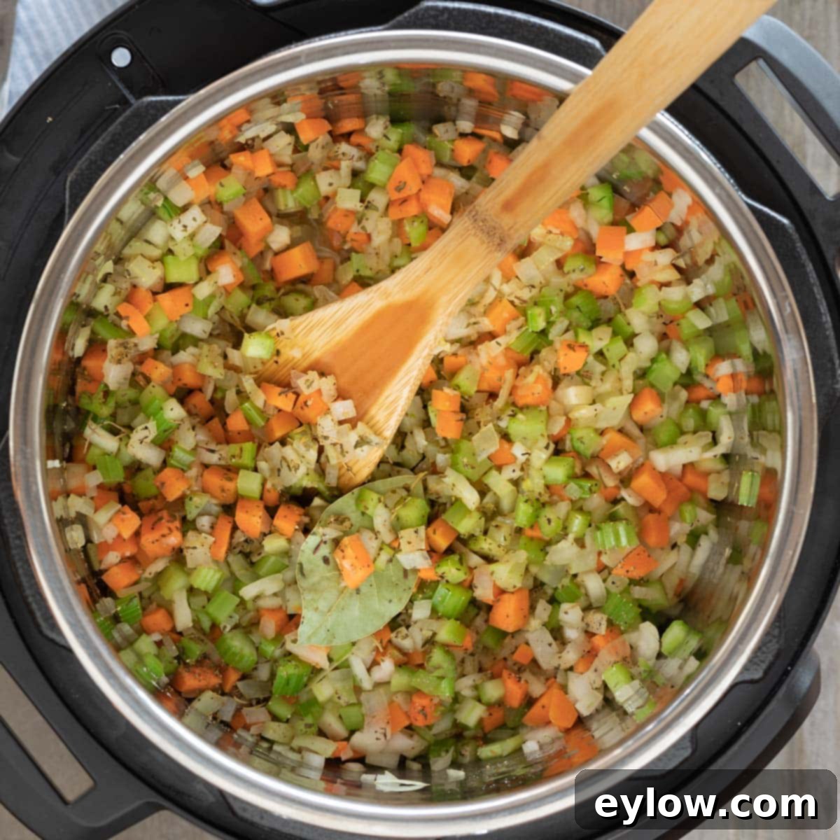 Vegetables sautéing in an Instant Pot before pressure cooking lentil soup.