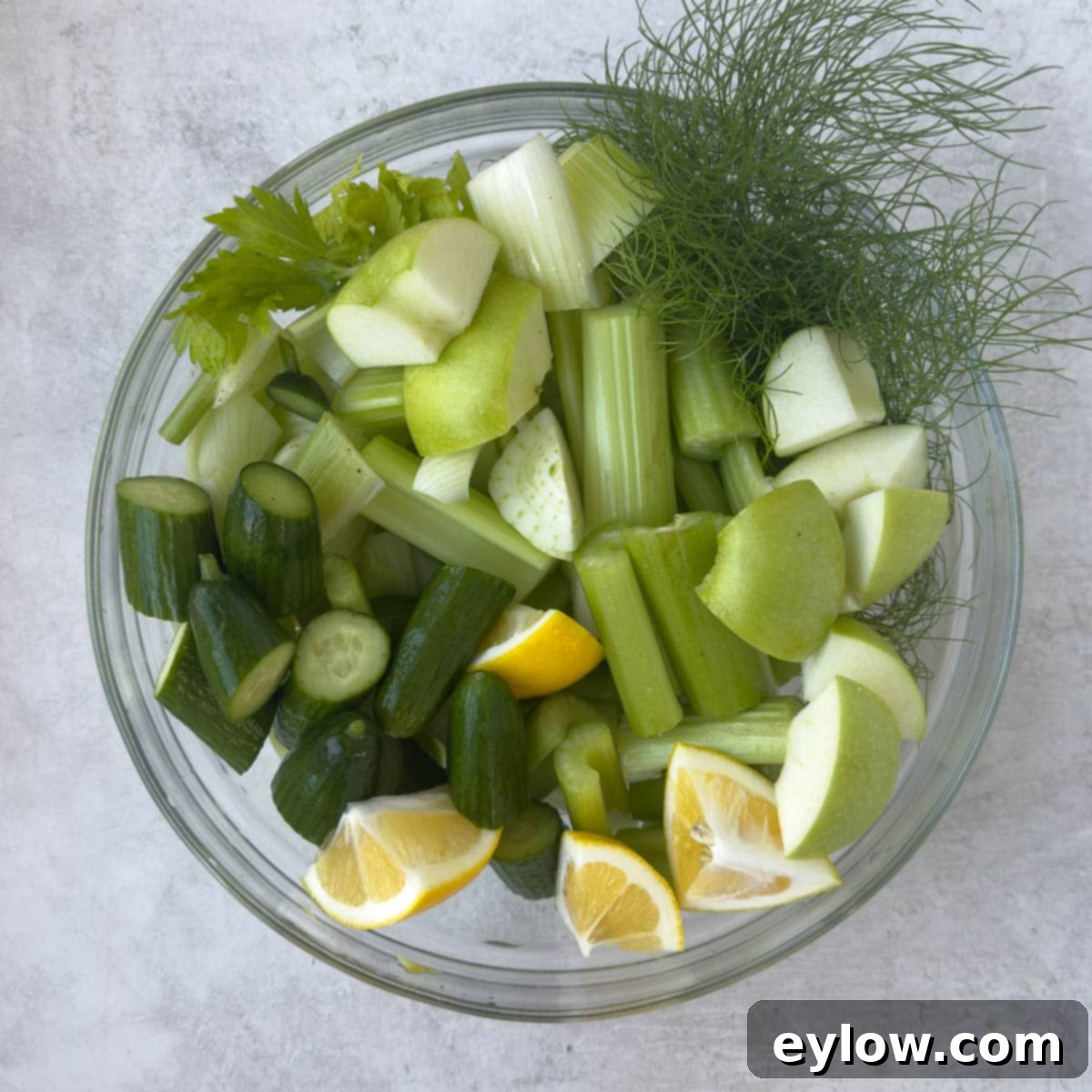 Crisp Green Elixir 5 A glass bowl of chopped vegetables, apples and lemon.