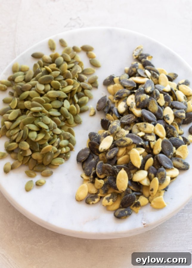 Two distinct varieties of pumpkin seeds displayed, with smaller, flat green pepitas on the left and larger, mottled yellow and blackish-green heirloom seeds on the right.