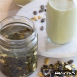 A jar of homemade pumpkin seed milk, showcasing its pale green color and creamy texture.