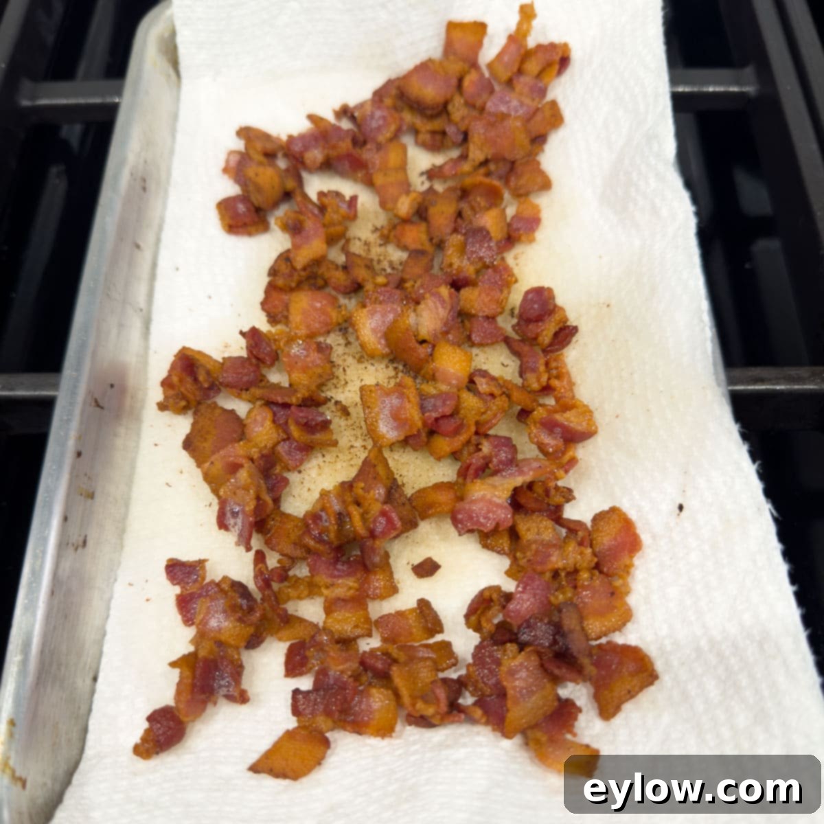 Crisply cooked bacon draining on layers of paper towels to remove excess grease.
