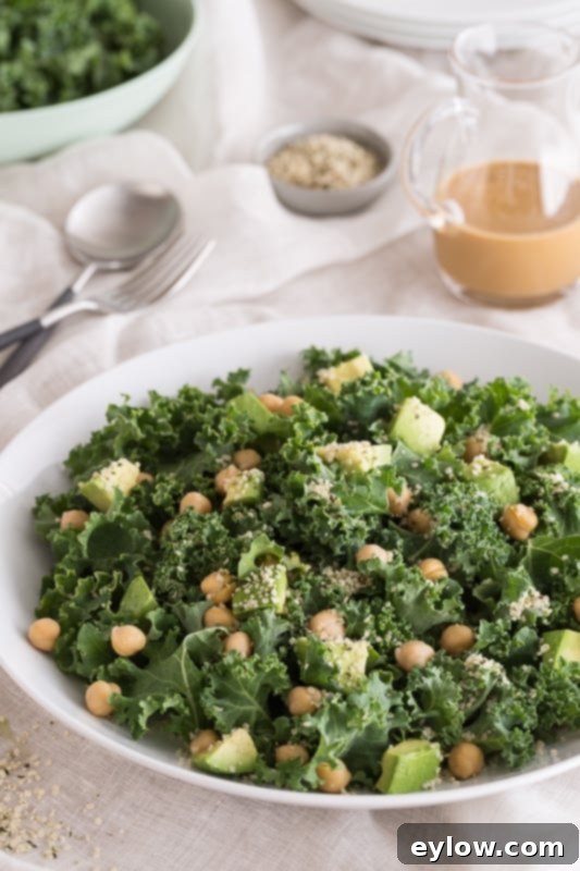 Kale salad with avocado and garbanzo beans dressed with tahini dressing.