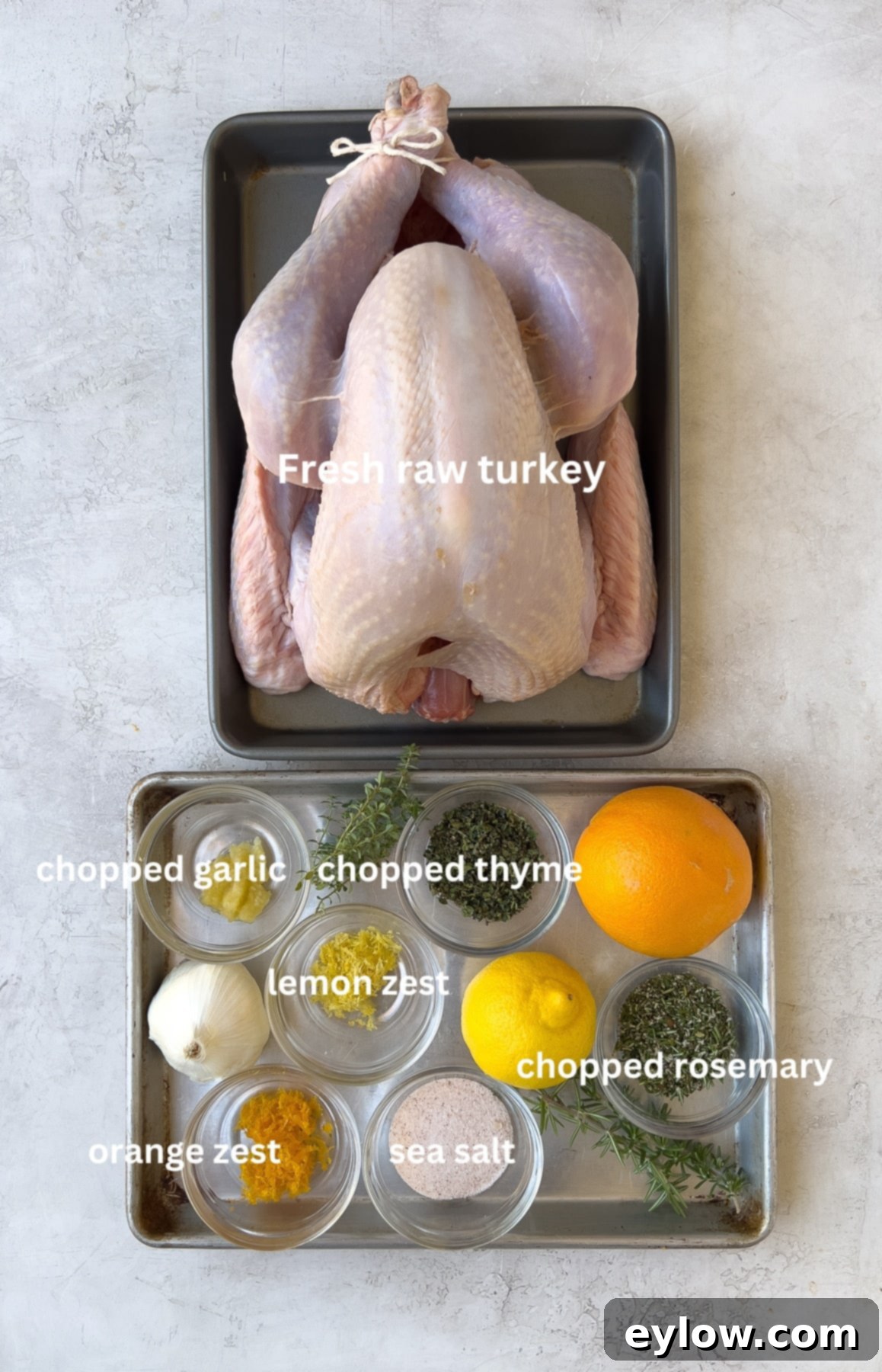 Turkey dry brine ingredients including kosher salt, fresh rosemary, thyme, lemon, orange, and garlic, laid out on a wooden surface.