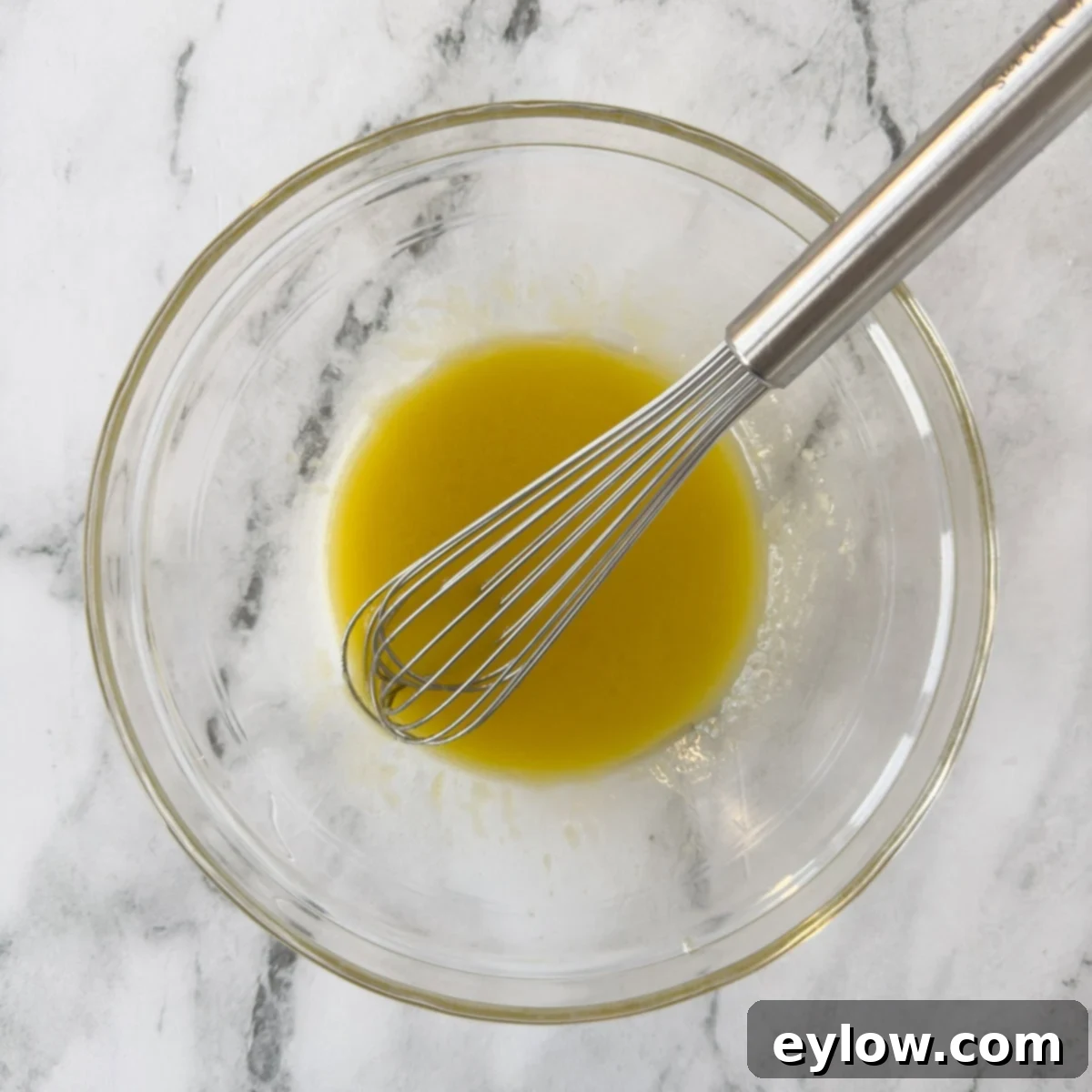 Vinaigrette whisked together in a glass bowl with a silver whisk.