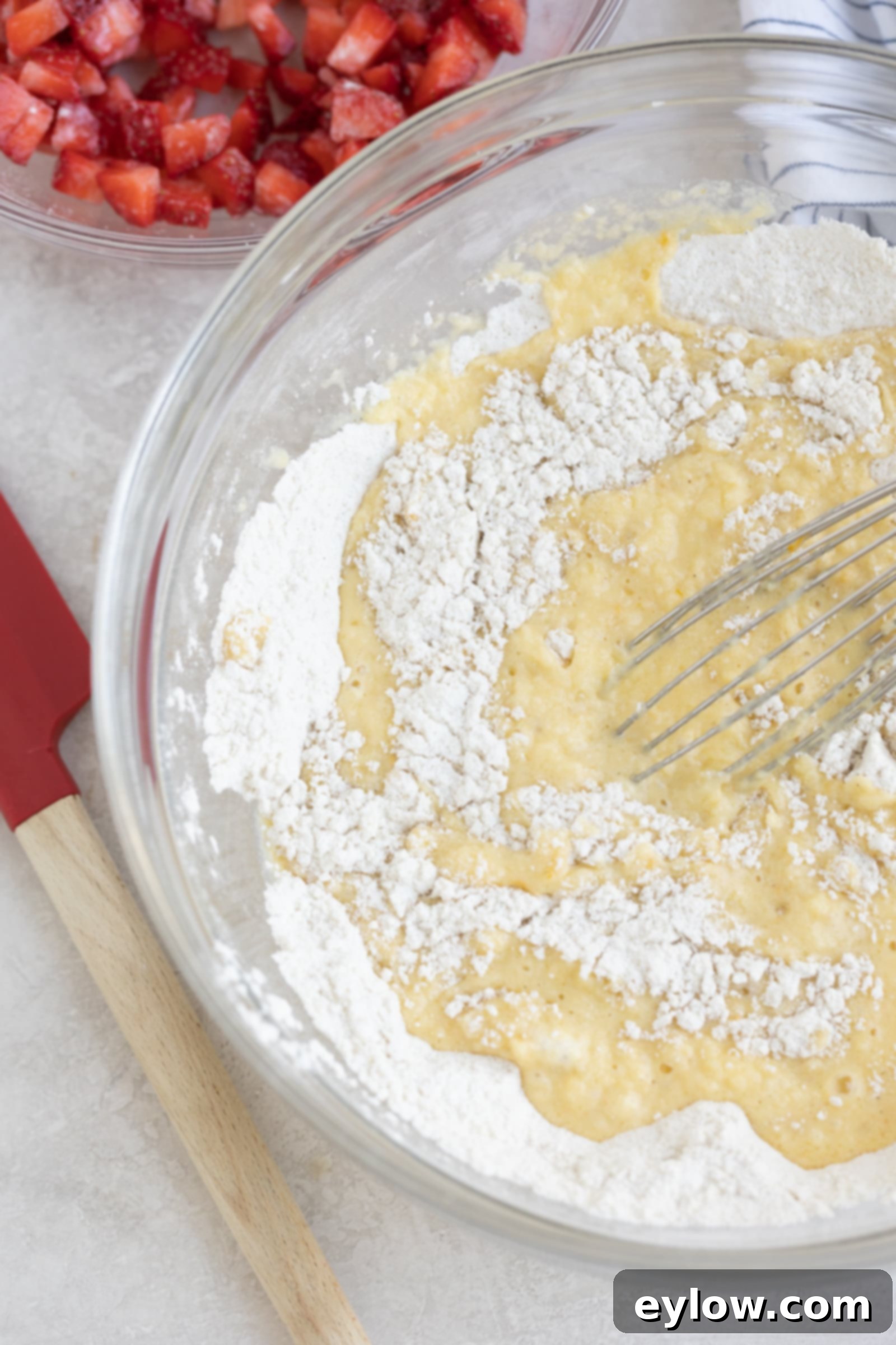 Fluffy Gluten-Free Strawberry Muffins 4 Strawberry muffin batter in a glass bowl with diced strawberries in the background.